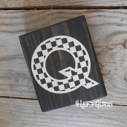 Block of wood with painted on checkered letter Q.
